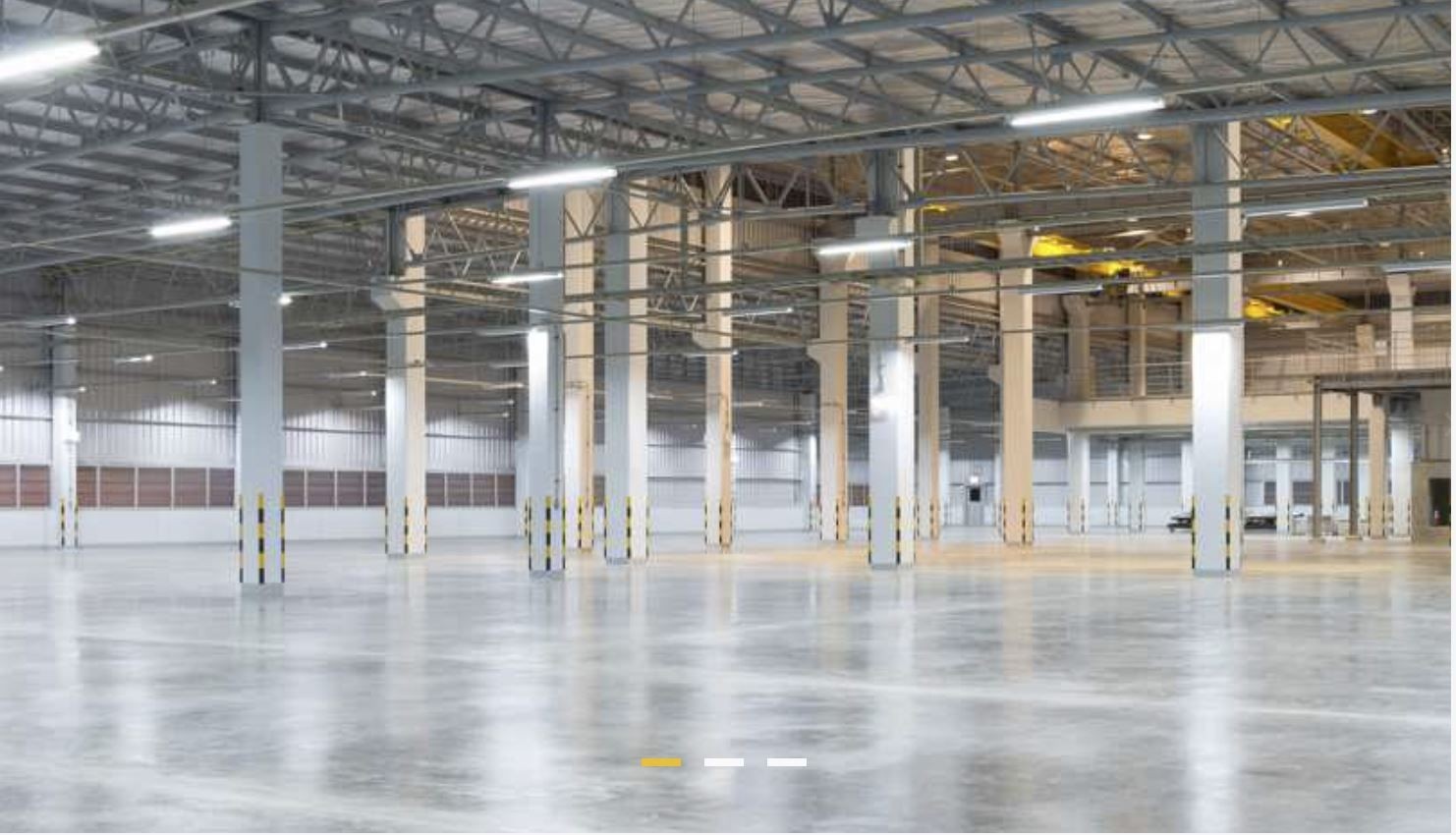 Interior view of a large, empty industrial warehouse with high ceilings and concrete floors.